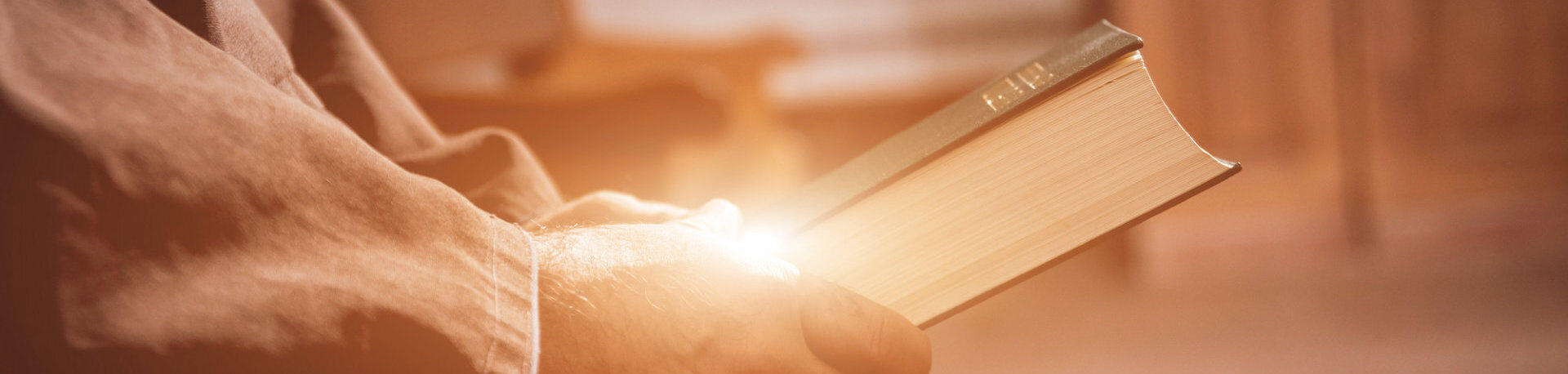 Pastor holding the Holy Bible with light reflecting off the hands.